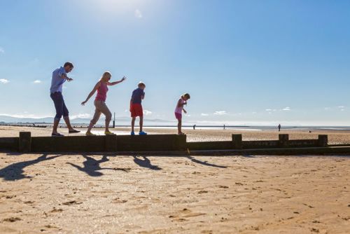 Teulu yn cerdded ar lan y môr Rhyl